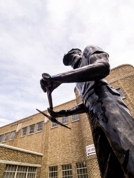 A metal statue of a railroad worker located in front of a library.
