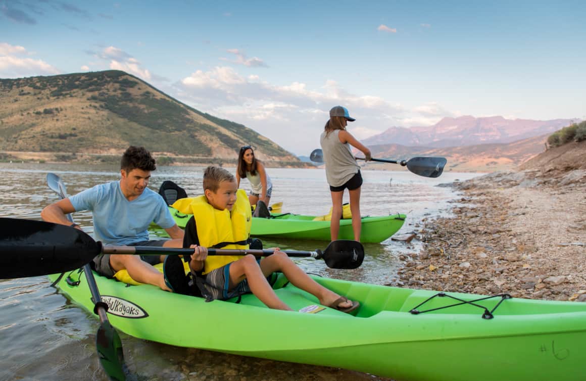 Colorful kayaks in bright greens, blues, yellows, and oranges dot the reservoir.