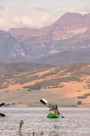 People kayaking on a lake with mountains in the distance.