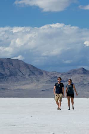 A man and woman walking their dog across a field of naturally occurring salt on the ground.