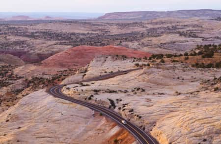 Expansive view of Utah's red rock landscape with Scenic Byway 12 winding through the terrain and two cars on the road.