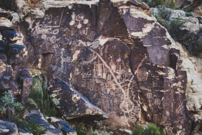 A wall of petroglyphs at Parowan Gap, etched into the weathered Navajo sandstone. These ancient carvings—including images of animals, people, and abstract symbols—offer a glimpse into the lives of those who once gathered here.