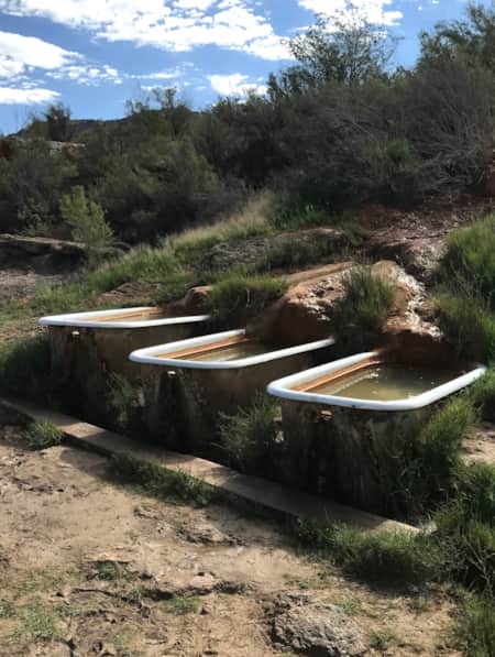 Three hot spring hot tubs built into the side of a rock.