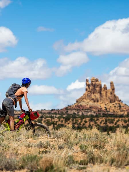 A woman bikepacking and looking at rock formations that resemble tall towers.