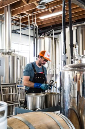 A man stands in a room surrounded by brewing equipment.
