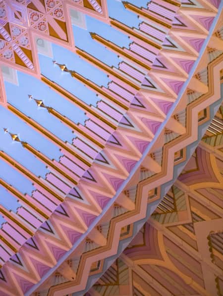 Close-up shot of a ceiling designed in an Art Deco theme, featuring intricate patterns in light pastel colors.