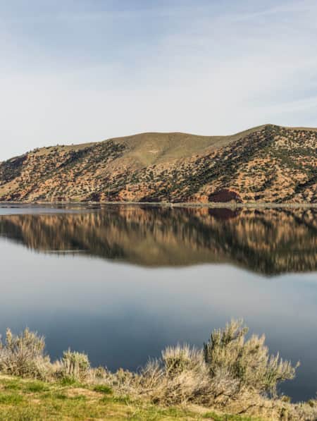 Blue skies at Echo Reservoir with the hills in the backdrop reflecting in the water.