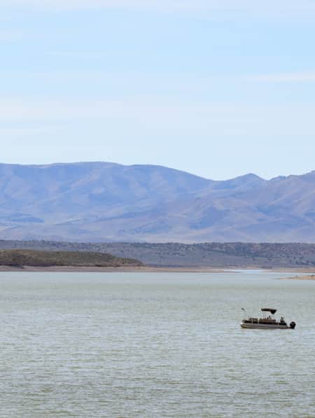 A lake with a boat and mountains in the background.