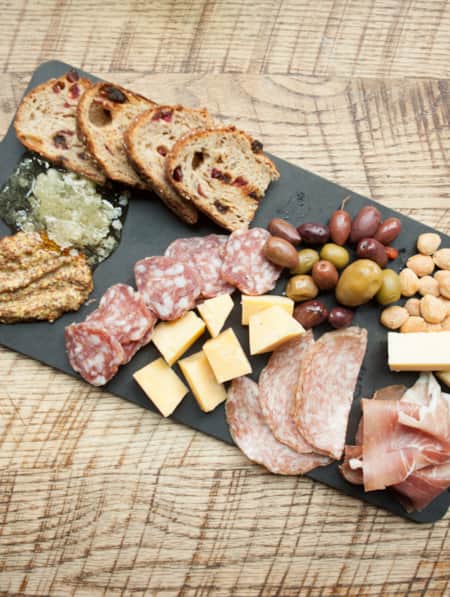 Charcuterie board with meats, cheeses, olives, almonds, and breads artfully arranged on a serving platter.