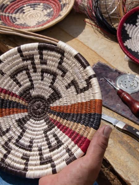 A person holding a handmade basket with intricate patterns.