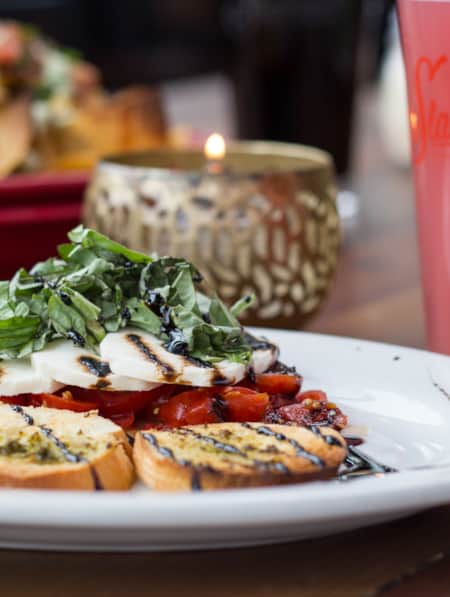 A plate of bruschetta with nachos in the background.