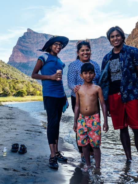 A family standing by a river in a canyon, all smiling.