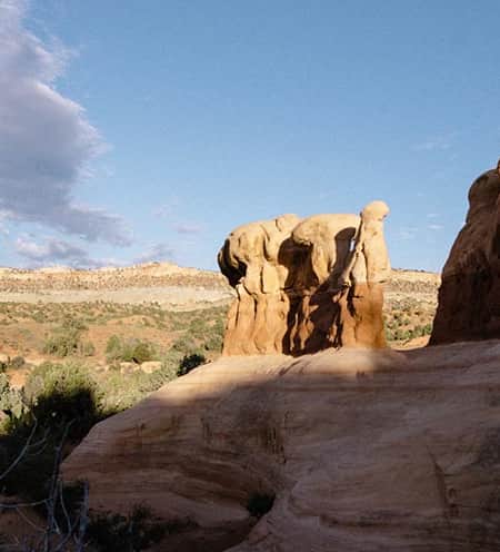 A scenic landscape of sparse vegetation, and various red rock formations.