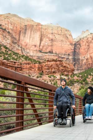 Two people in wheelchairs explore an accessible trail in Zion National Park.
