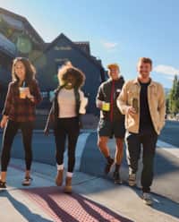 Group of four friends, holding coffees and walking through downtown Park City.
