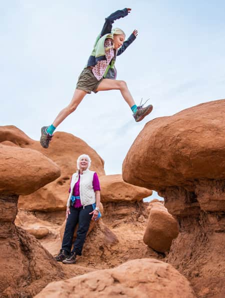 Young girl jumping across the goblins of Goblin Valley State Park.